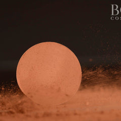 Powder compact, round, peach color with powder dust, Boss Cosmetics logo visible