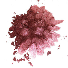 Eyeshadow powder in shimmering burgundy and pink shades, scattered on white surface