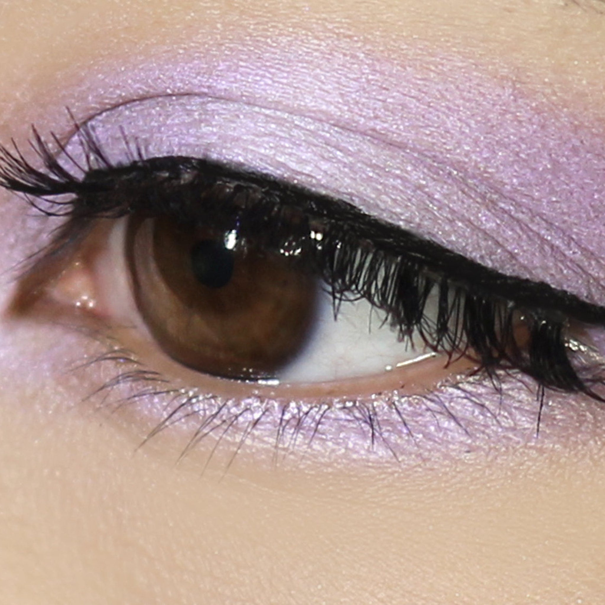 Eyeshadow makeup with lilac shimmer and black eyeliner on an eye