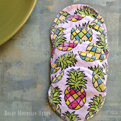 Reusable facial rounds with pineapple pattern, white stitched edges, and Rocky Mountain Herbs text
