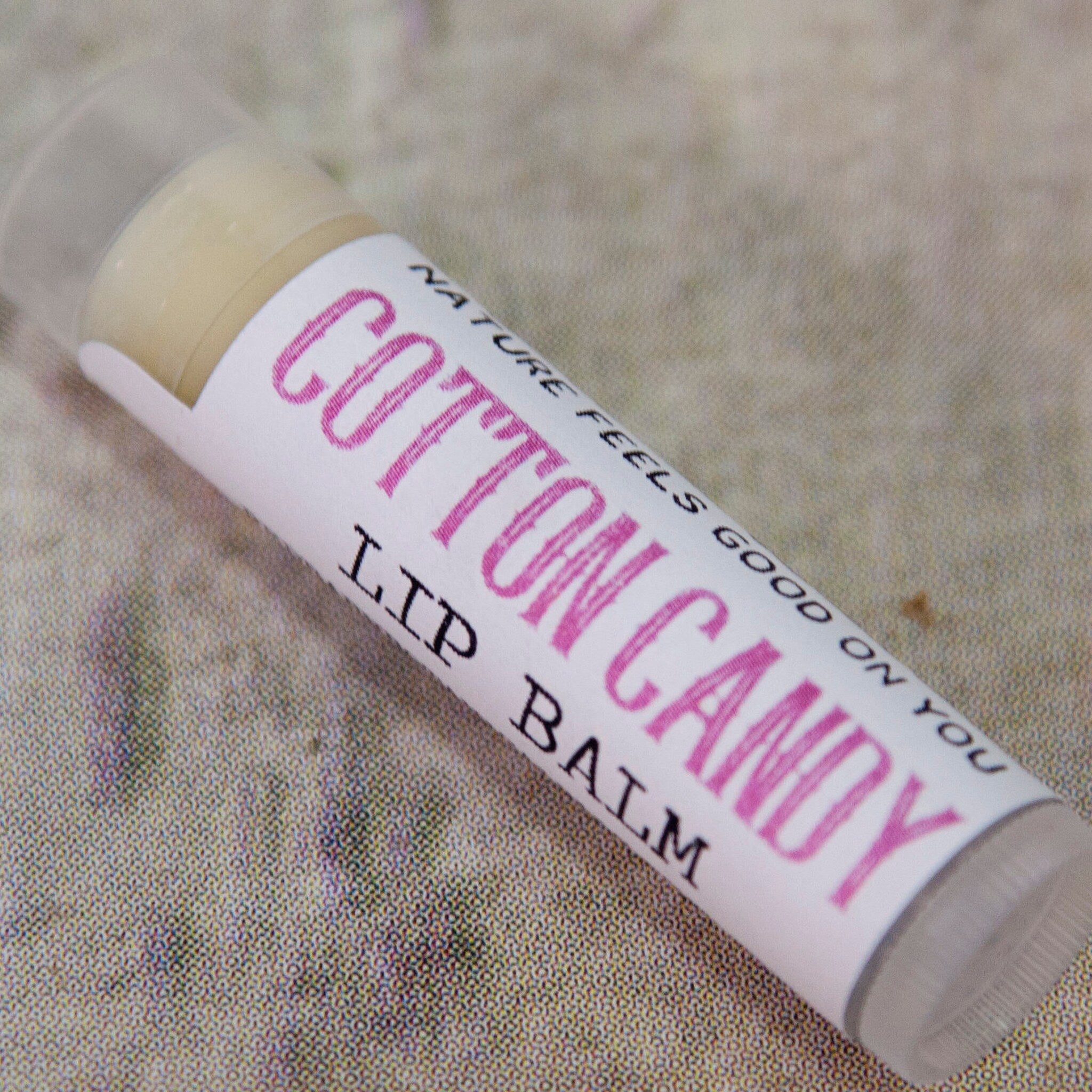 Lip balm tube with white label, pink text, and clear plastic casing