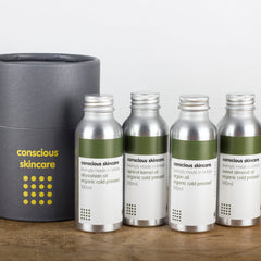 Skincare bottles with silver metal, green labels, and brand text, arranged on wooden surface
