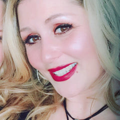 Woman with blonde hair, red lipstick, and silver hoop earrings smiling at camera
