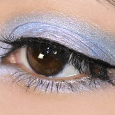 Eye makeup blue eyeshadow with pink and turquoise shimmer applied to eye, close-up