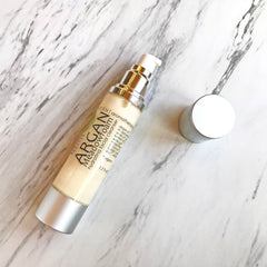 Facial cleanser bottle with silver and white accents, cream liquid, and brand text on marble surface