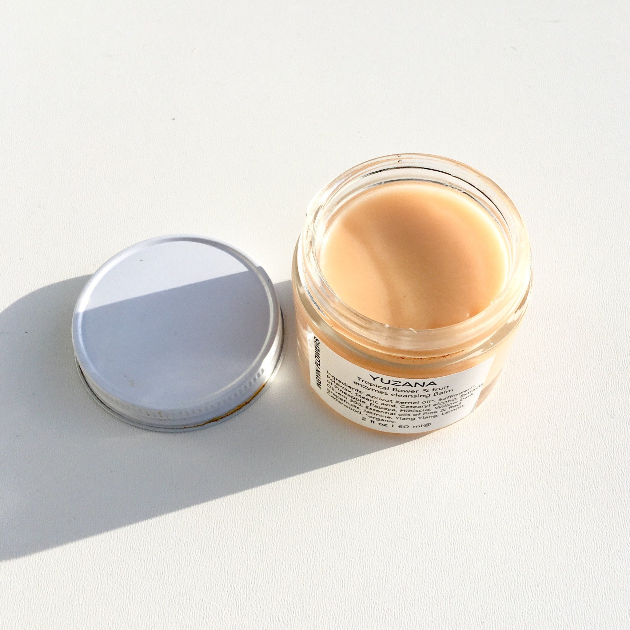 Facial cleanser jar with light peach balm, glass and silver lid, YUZANA label visible