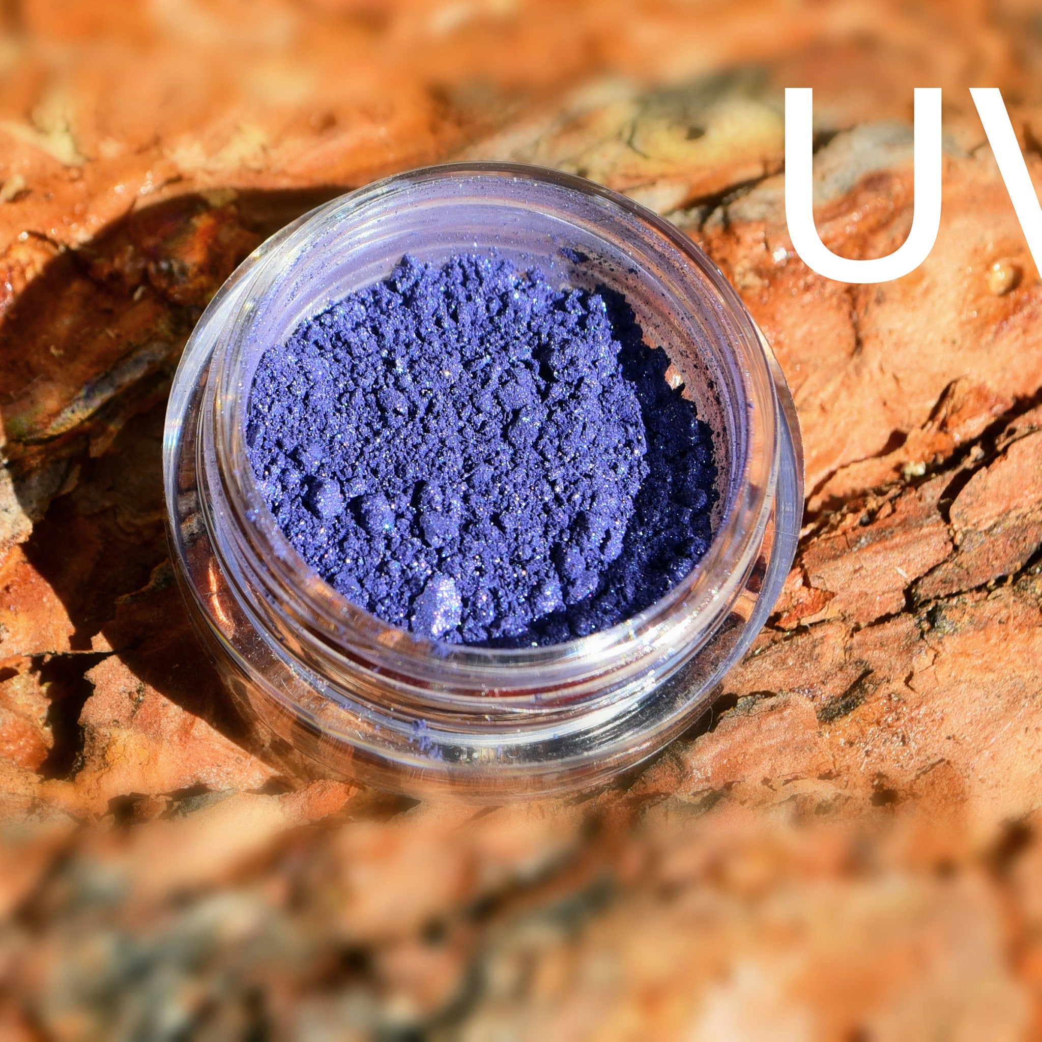 Small round jar of pigmented mineral eye shadow with UV protection and built-in sifter, showcasing rich color payoff