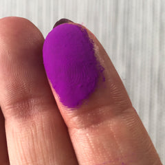 Close-up of fingers applying vibrant purple Tala Neon Pigments eye shadow with shimmer finish