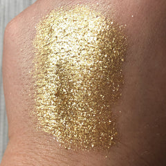 Gold glitter eyeshadow swatch on skin, showing metallic sparkle and texture