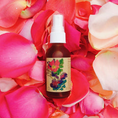 Toner bottle with white cap and brown glass, surrounded by pink and red rose petals