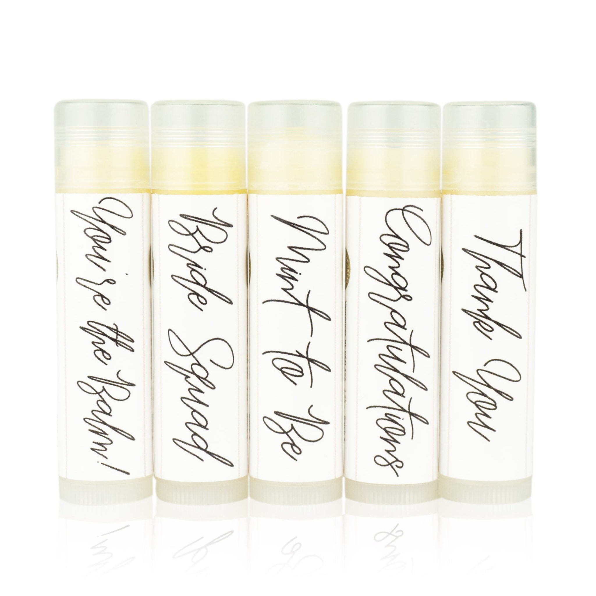 Lip balms with white labels, black script text, and clear tubes