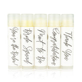Lip balms with white labels, black script text, and clear tubes