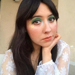 Close-up of matte green eyeshadow being applied to eyelid with a blending brush