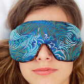Travel sleep eye mask with blue brocade pattern and brown velvet trim, worn on face