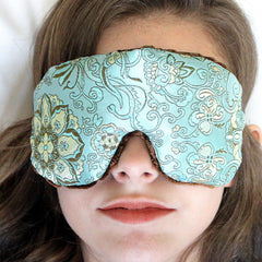 Eye mask with blue floral brocade pattern and brown velvet trim, worn over eyes