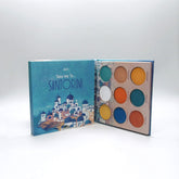 Eyeshadow palette with blue, white, and colorful eyeshadows, Mavie Santorini palette open on white background