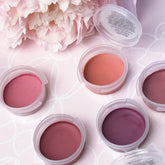Lipstick samples in various shades of pink and purple, in clear plastic containers, on a floral background