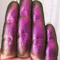 Glittery purple and green finger paint, showing texture and color variation, on fingers