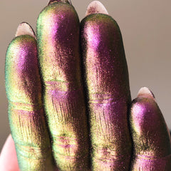 Iridescent fingers with purple, green, and gold color shift, showing texture, and white nail tips