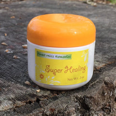 Skin care salve jar with orange lid, white jar, and yellow label, Forest Hills Remedies
