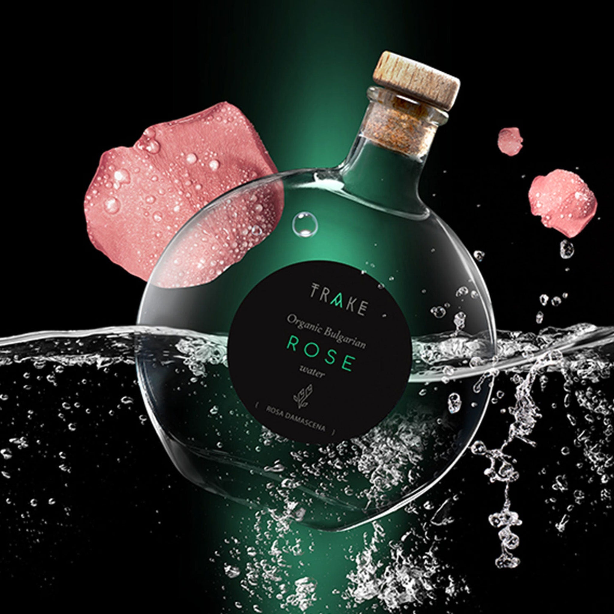 Rose water bottle with TRAKE label, glass, cork, and pink rose petals in water