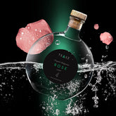 Rose water bottle with TRAKE label, glass, cork, and pink rose petals in water