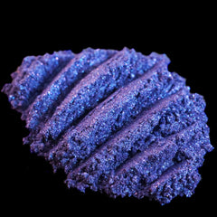 Side view of loose dark purple mineral eyeshadow with shifting indigo glitter in a small jar