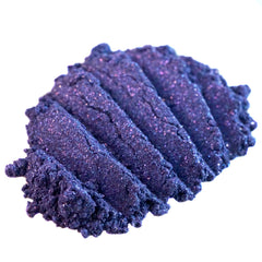 Close-up of dark purple loose pigment eyeshadow with shifting indigo glitter and metallic violet sheen