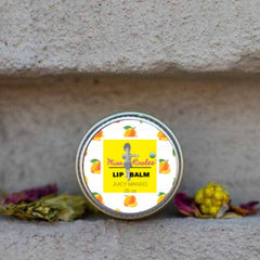 Lip balm tin with white and orange mango pattern, yellow label, and Miss Kinslee text on stone surface