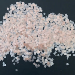 Glitter flakes in hexagonal shape, light pink and white, scattered on black background