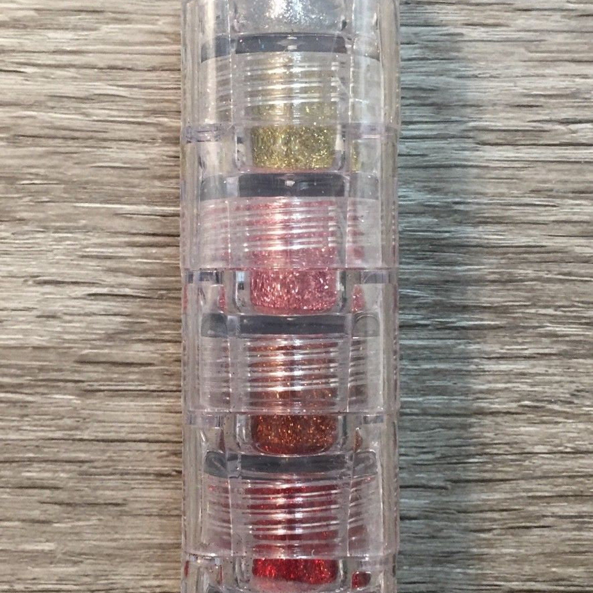 Stack of five jewel-toned mineral eye shadows with glitter finish in a sleek black compact