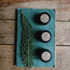 Eye shadow pots in black with Moonrise Creek labels on teal book and wood background