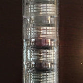 Eye makeup stack in clear plastic with silver bands, stacked vertically on a dark surface