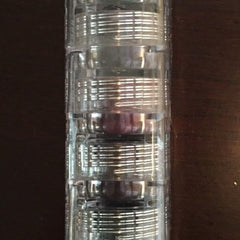 Eye makeup stack in clear plastic with silver bands, stacked vertically on a dark surface