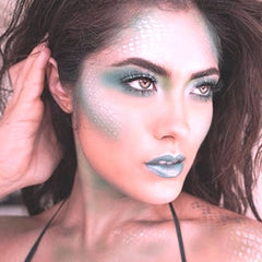 Hand applying holographic white vegan eyeshadow with fingertip for a sparkling fairy Halloween look