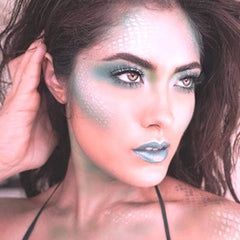 Mermaid makeup with teal eyeshadow, scale pattern, and blue lipstick on a person's face