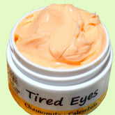 Eye cream in white jar with peach cream, "Tired Eyes" text visible, Bodhitreenaturals brand