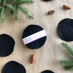 Facial rounds black cotton rounds with Farm Girl Design label and pinecones on surface