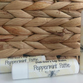Lip balm tubes, white with yellow pattern, Deb*bee's Peppermint Pattie text, near woven basket