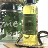 Face toner bottle with yellow liquid, green label, and myHerbalicious branding, on a wooden surface