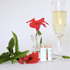 Lip balm tubes with Organic Radiance Cosmetics label, clear tubes, light pink balm, flowers and champagne glass