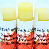 Lip balm tubes with yellow balm, white labels, and strawberry graphics, Ancient Bath and Body brand