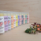Lip balm tubes with colorful labels, LB Love branding, arranged in a row on wood surface