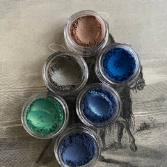 Close-up of shimmering green gold vegan mineral eyeshadow with sparkling flecks in compact pan