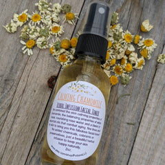 Facial toner bottle with black cap, yellow liquid, and chamomile flowers on wood surface
