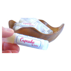 Lip balm tubes with "Cupcake" label, white and blue polka dot pattern, in a wooden bowl