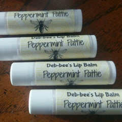 Lip balm tubes with white and light yellow labels, black text, and bee graphic, Deb-bee's brand