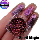 Multichrome eyeshadow flakes in shifting iridescent hues, scattered on a smooth surface