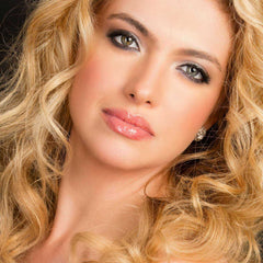 Blonde wavy hair with makeup and a diamond earring, portrait view of a woman