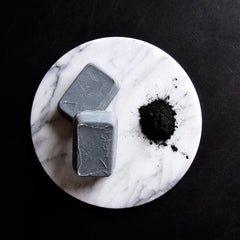 Gray soap bars on white marble, with black powder and black background